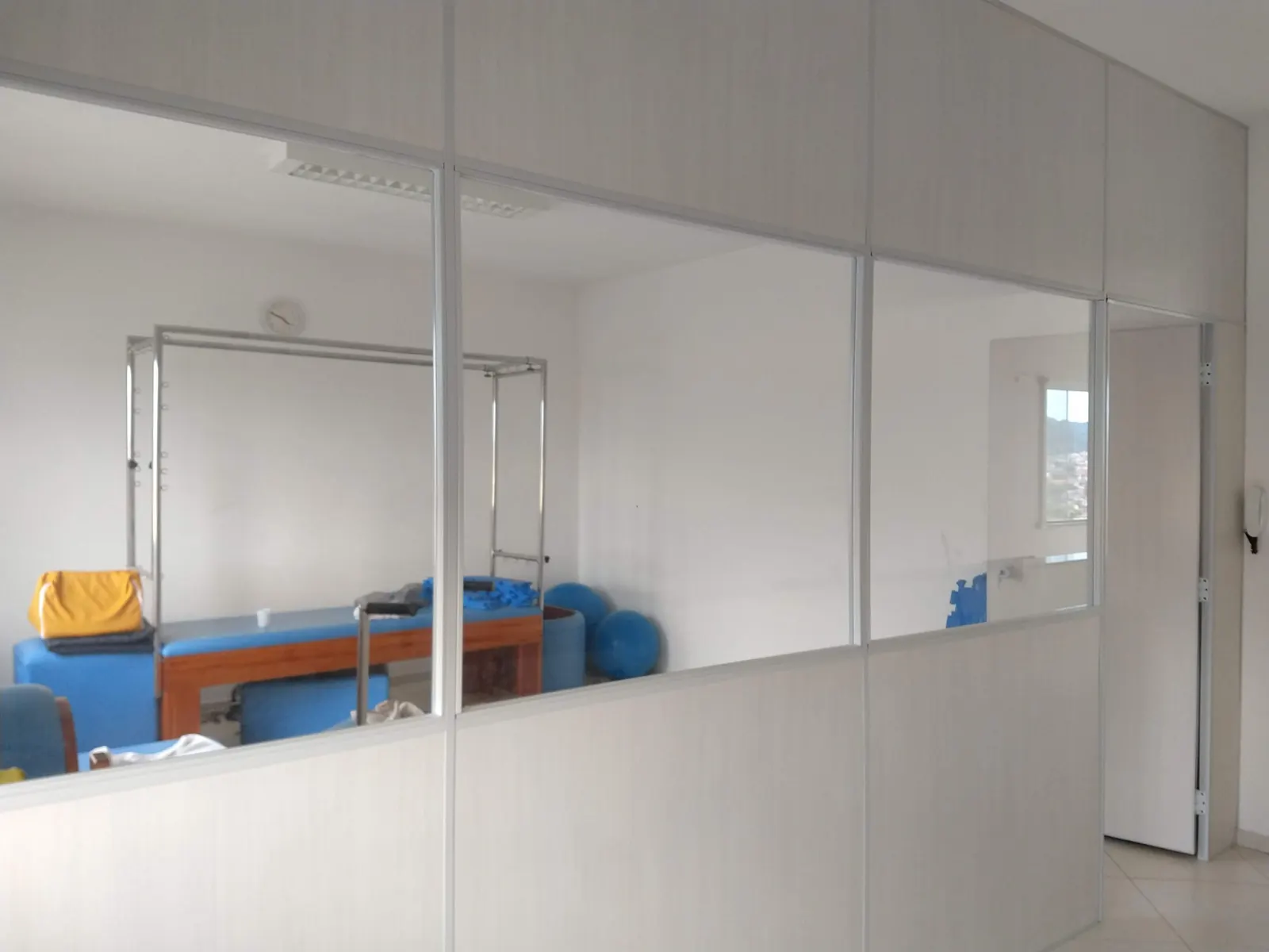 Sala dividida com divisórias brancas e vidro